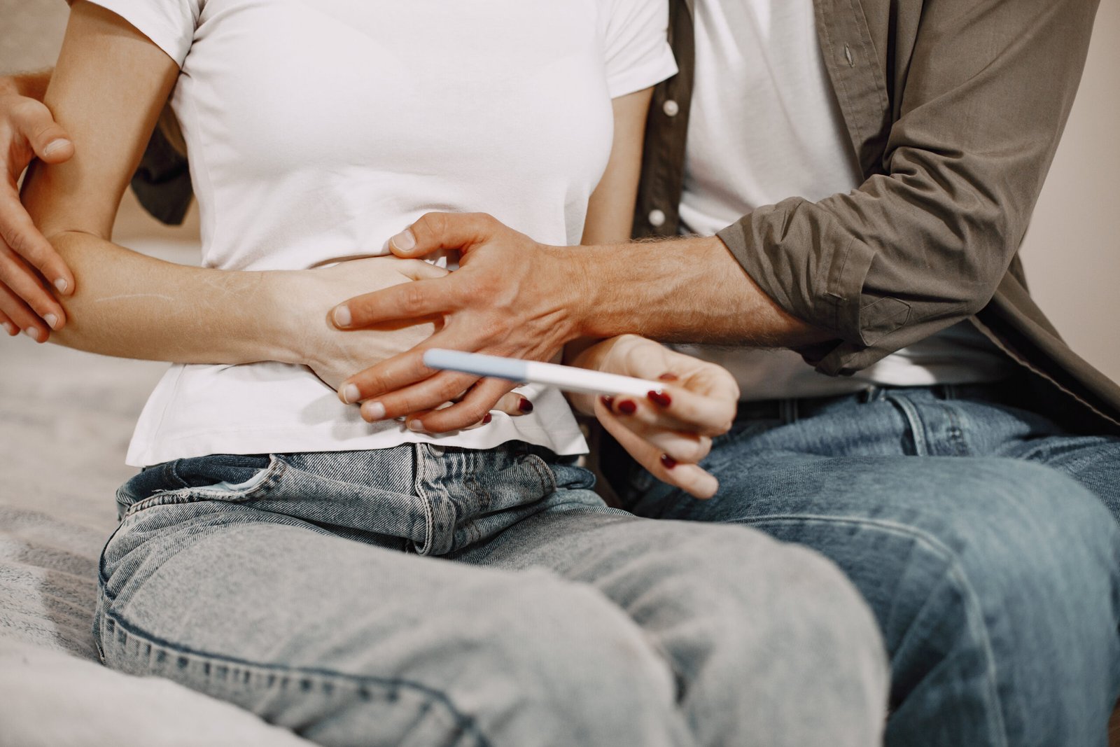 A couple sitting together, holding a pregnancy test while embracing, symbolizing fertility preservation and future family planning.